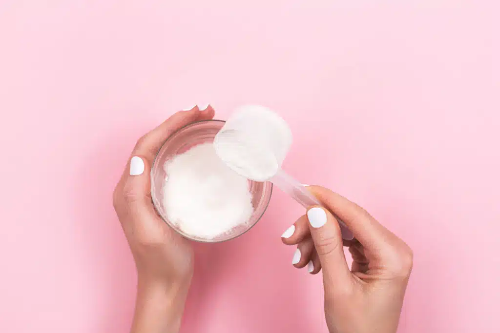 Woman hands with a scoop with collagen or protein powder